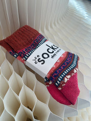 Red patterned socks with a visible brand label on a textured white background