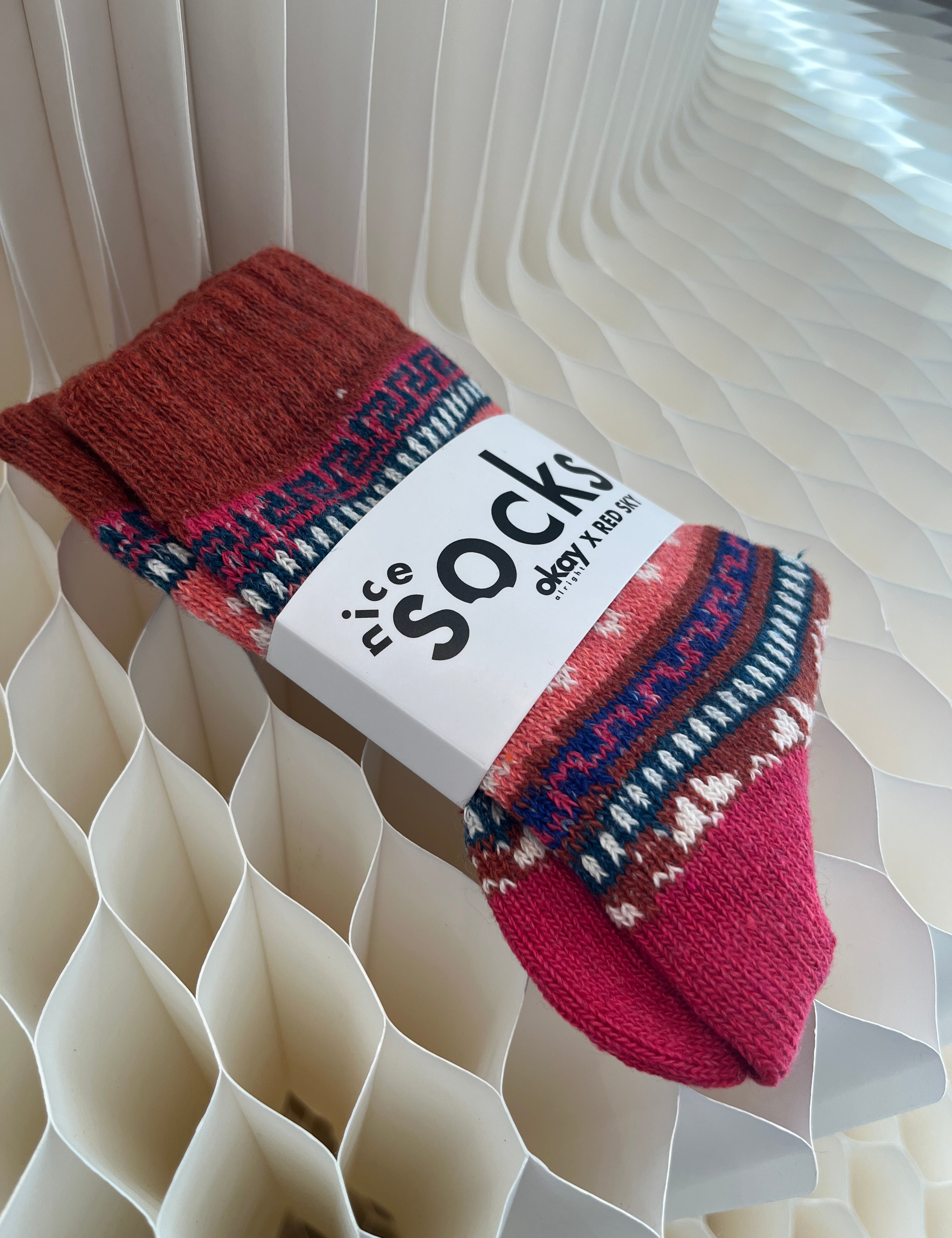 Red patterned socks with a visible brand label on a textured white background