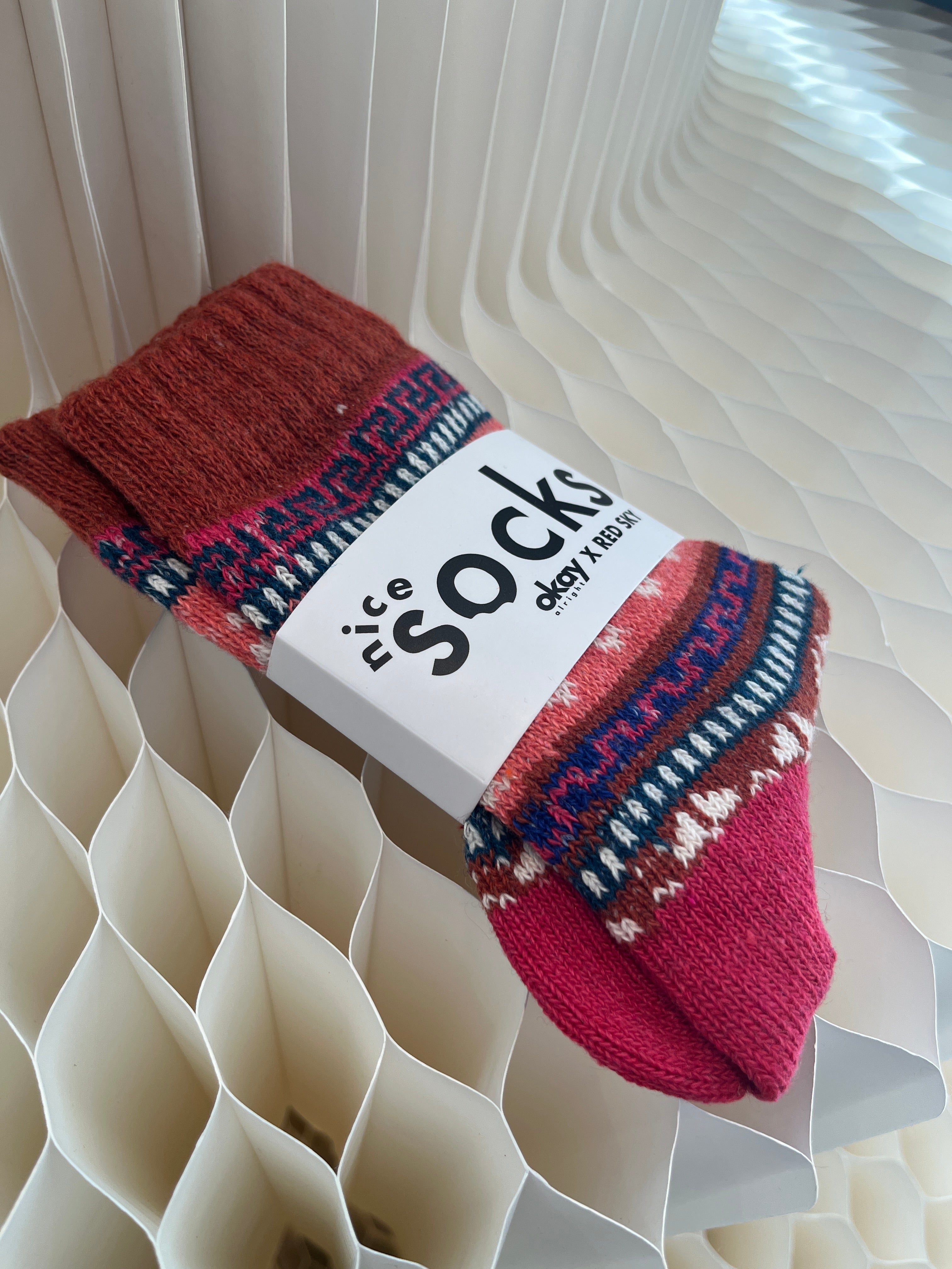 Red patterned socks with a visible brand label on a textured white background
