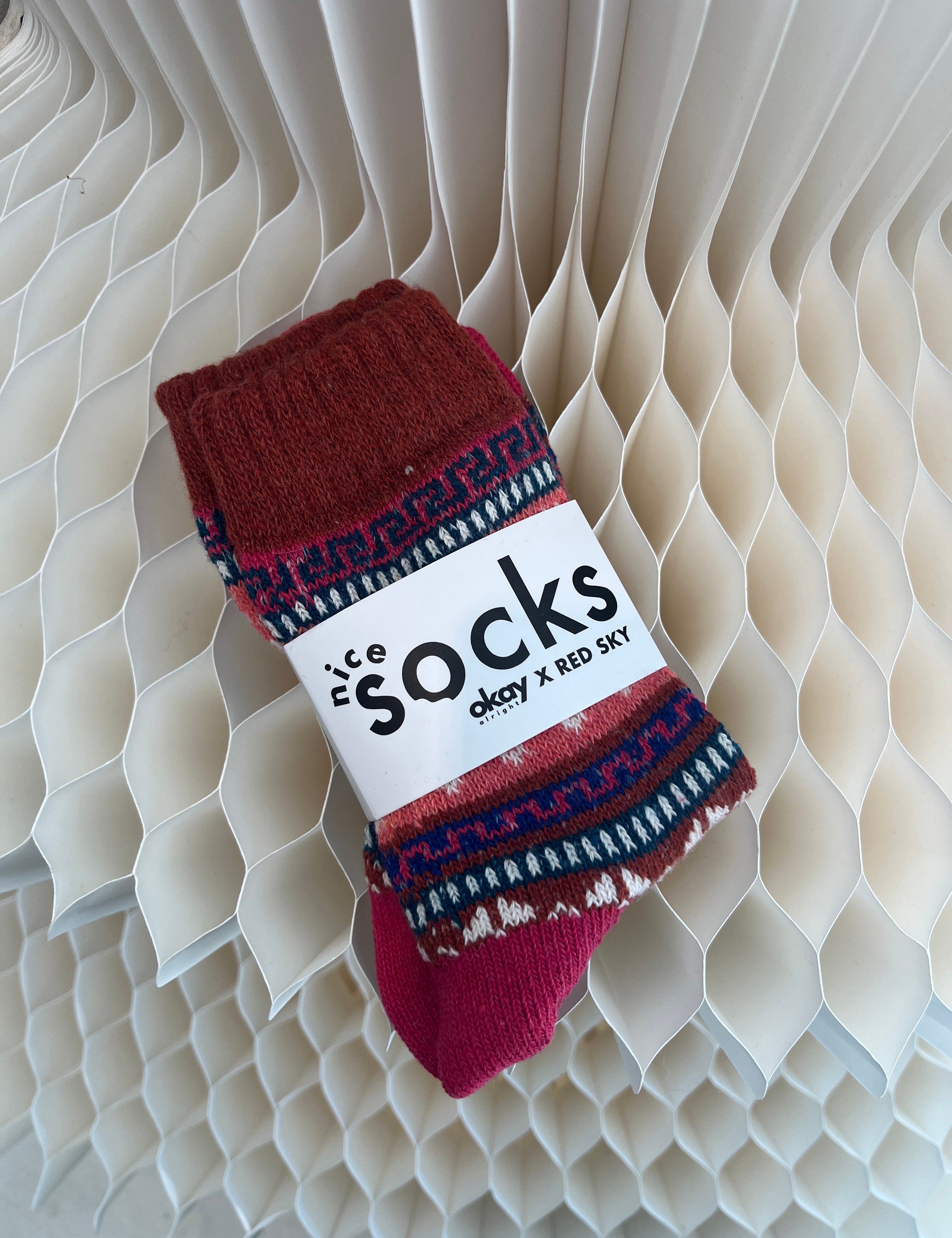 Red and blue patterned socks on a white label with text against a textured beige background