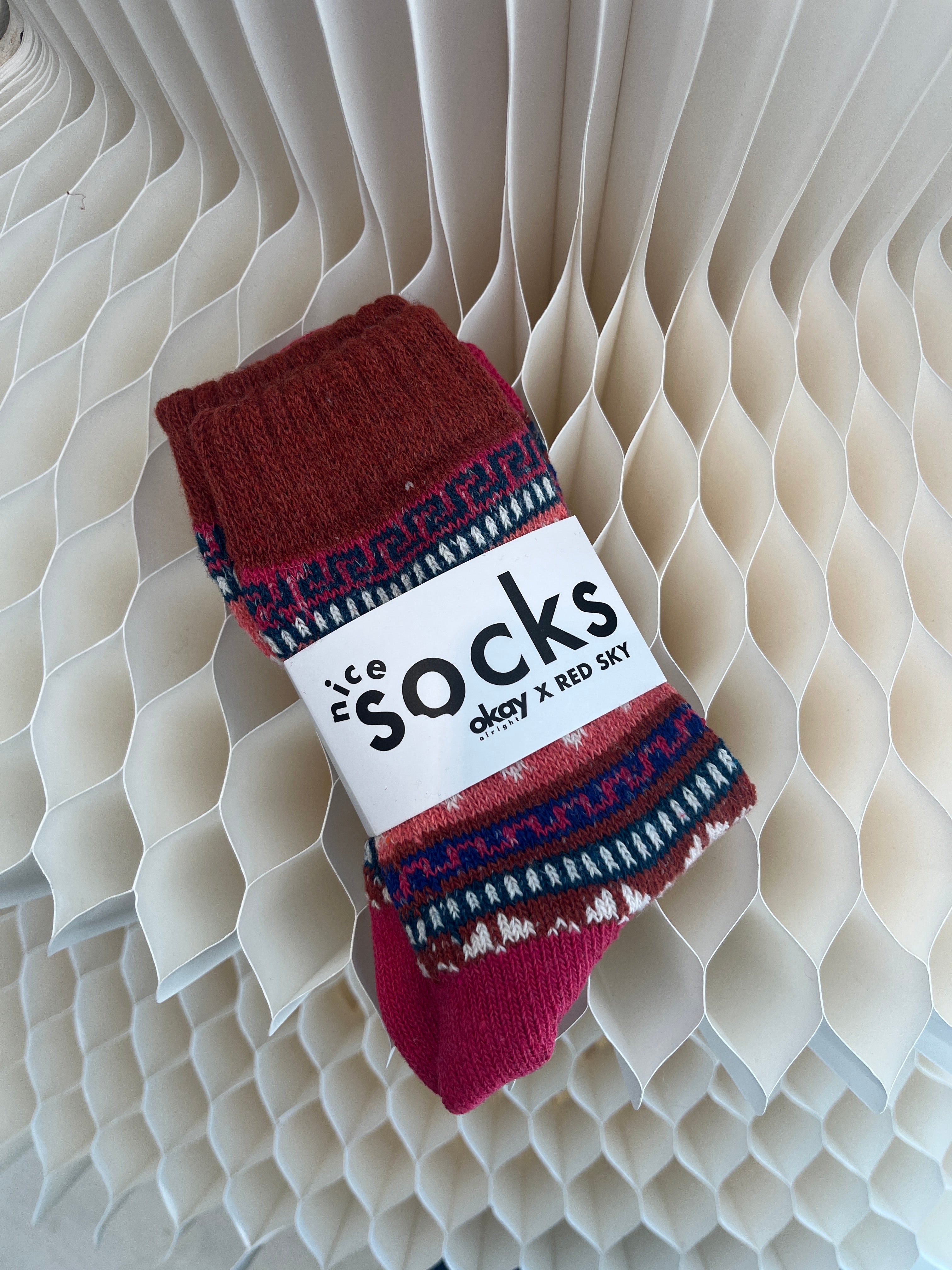 Red and blue patterned socks on a white label with text against a textured beige background